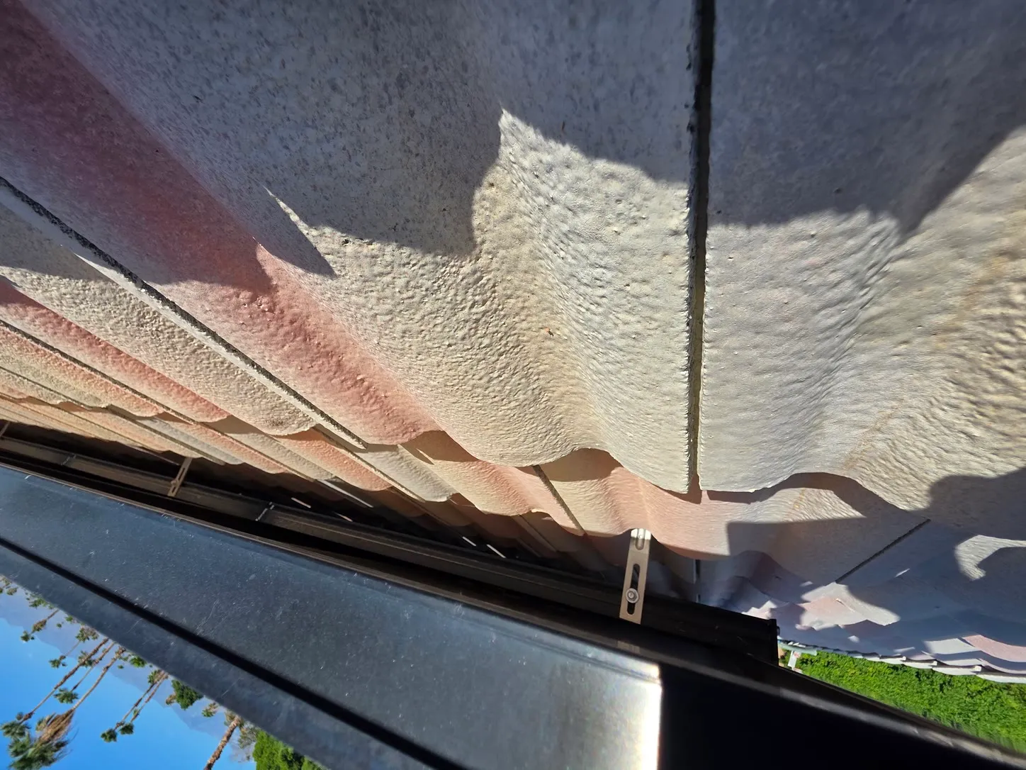 Job photo: the open, unguarded gap beneath a solar array on a Cathedral City tile roof, the space pigeons nest in