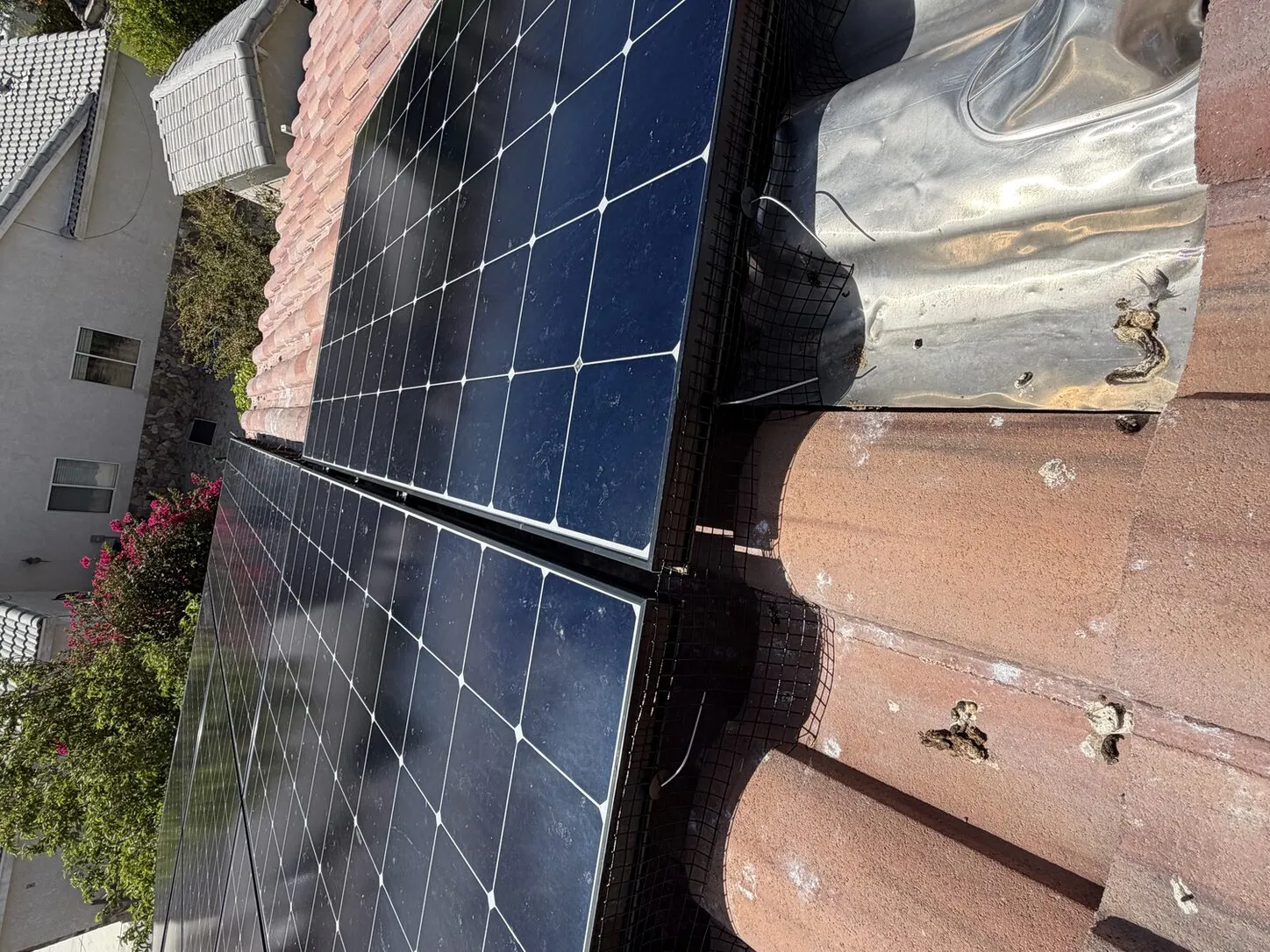 Job photo: critter mesh fitted beneath a solar array on a clay-tile roof