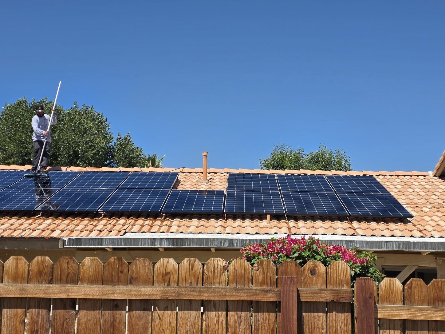 Job photo: a Clear Flow technician on a Palm Desert tile roof cleaning solar panels with a water-fed pole