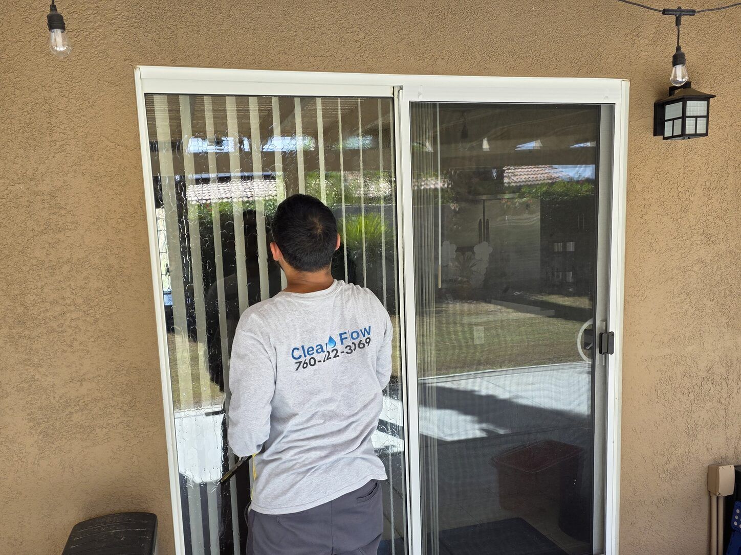 Job photo: a Clear Flow technician in a branded shirt cleaning a sliding glass door on a Cathedral City patio