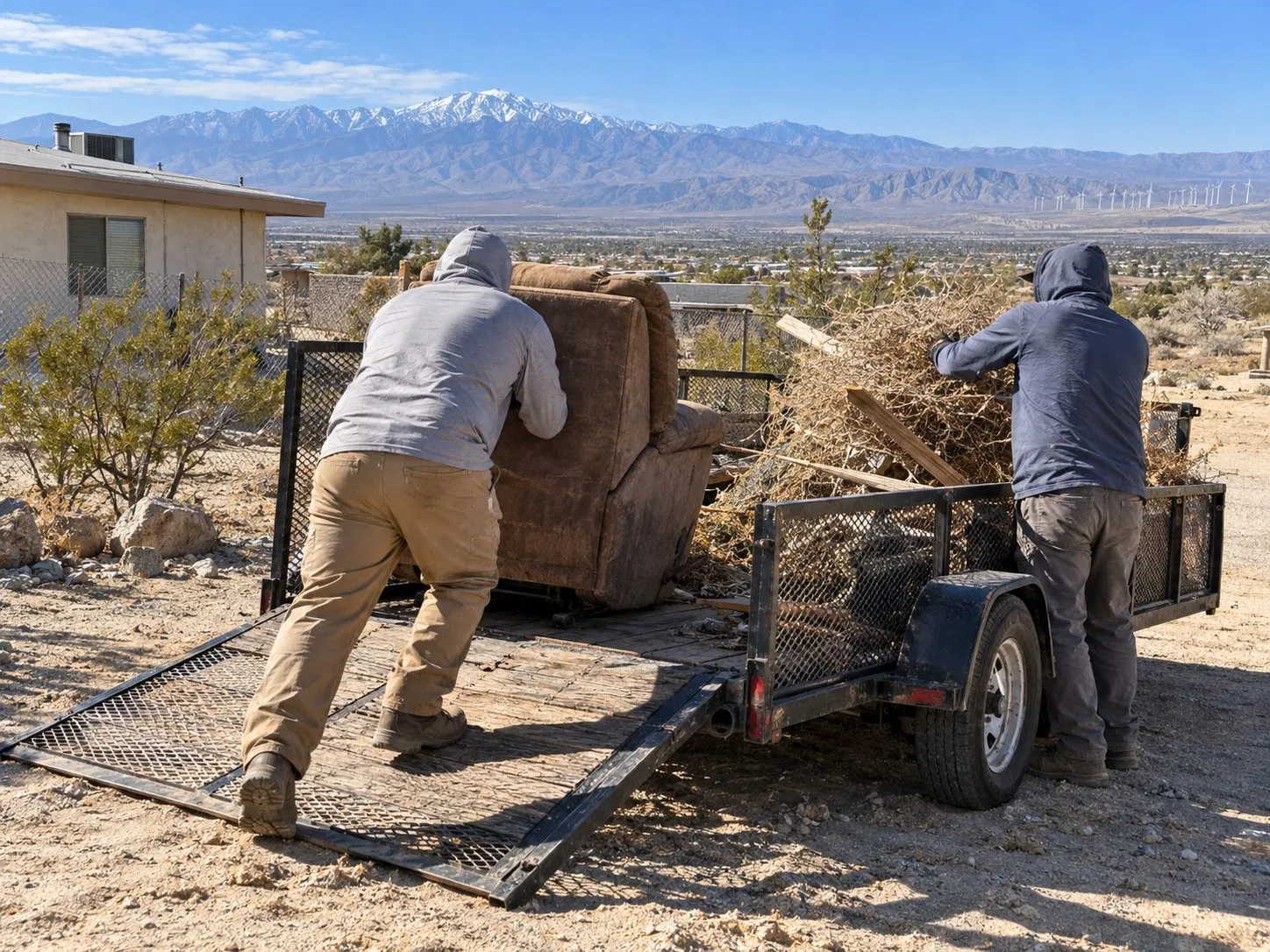 Service illustration: workers loading tumbleweeds and old furniture into a trailer in Desert Hot Springs
