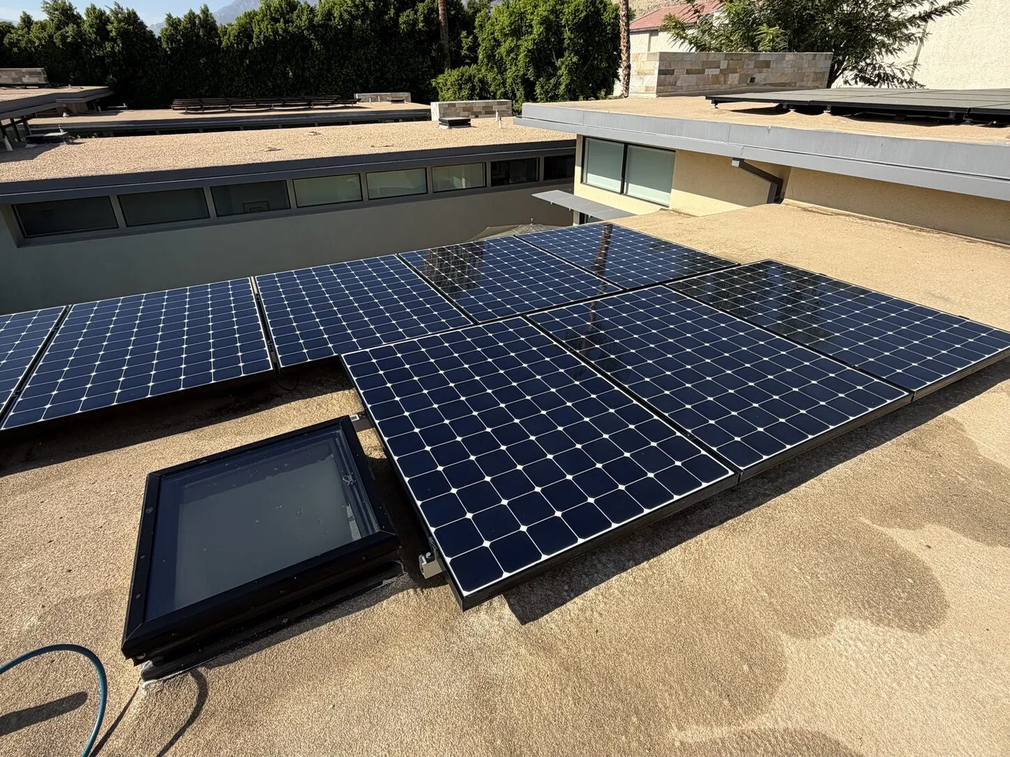 Job photo: gray, dusty panels beside a skylight on a Palm Springs flat roof, and the same panels clean