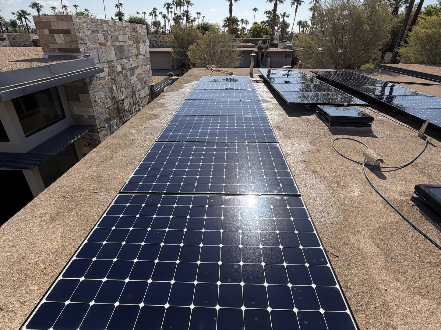 Job photo: freshly cleaned solar rows on a Palm Springs mid-century flat roof with a stone chimney