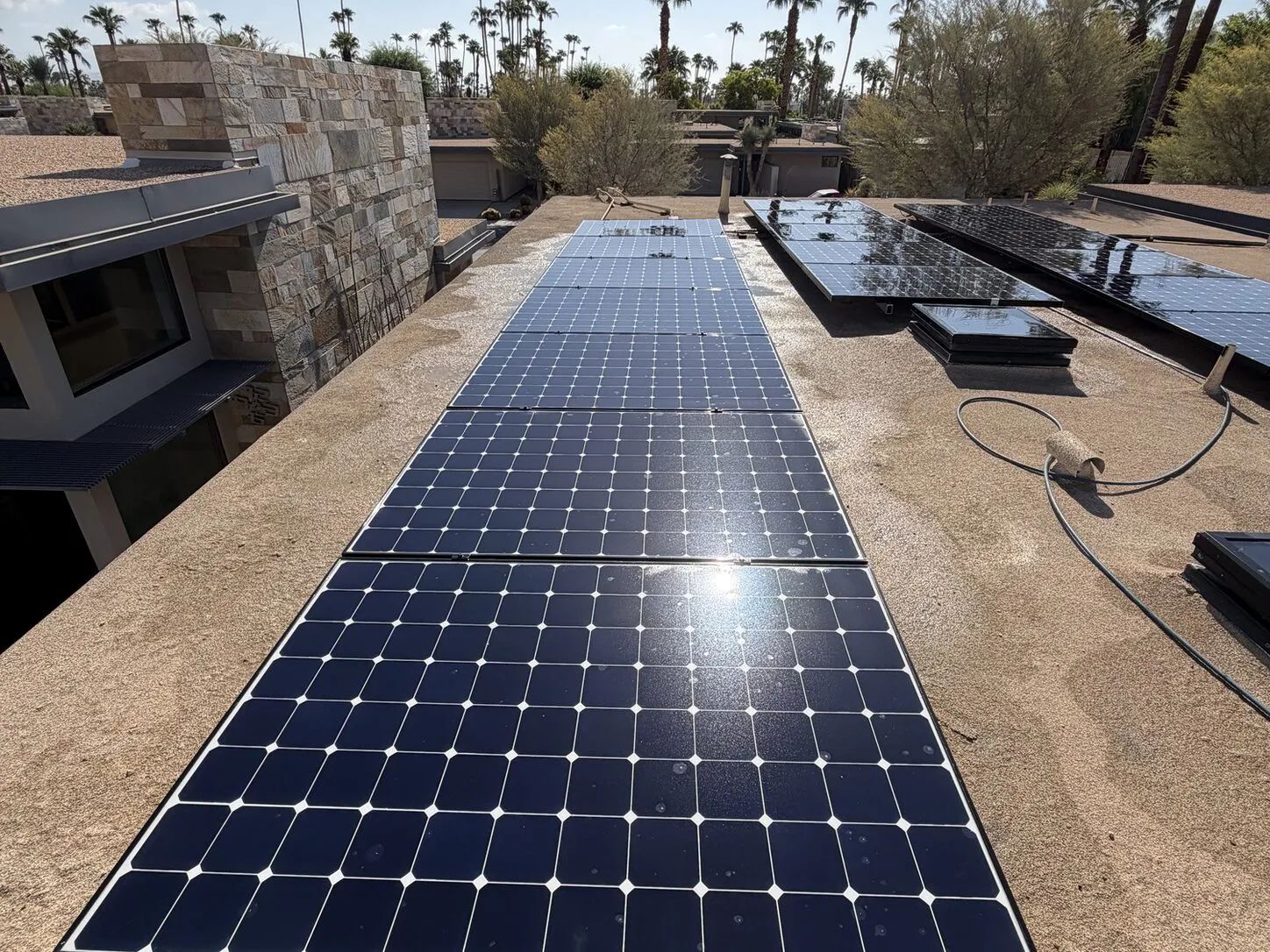 Job photo: freshly cleaned solar rows on a Palm Springs mid-century flat roof with a stone chimney