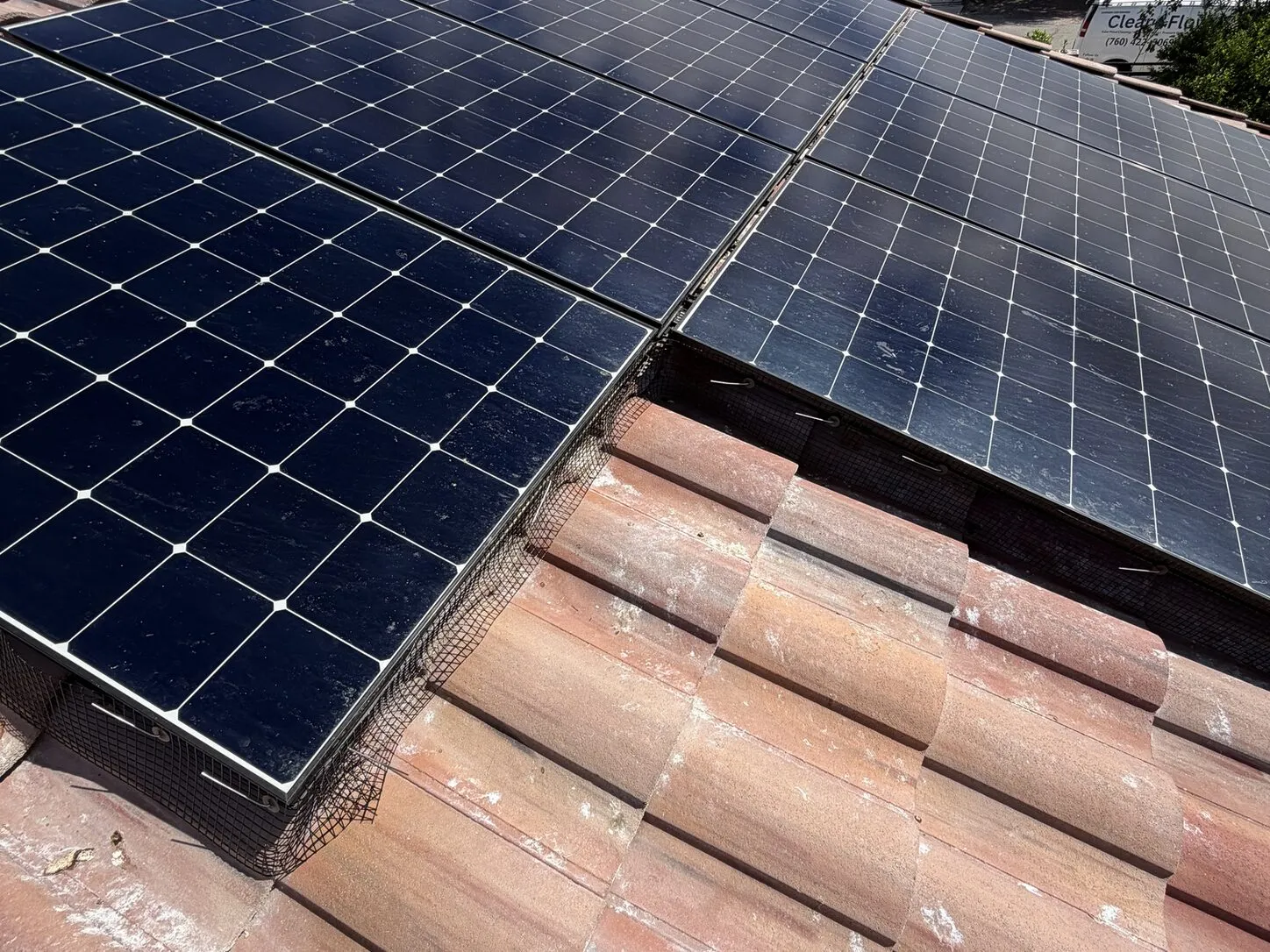 Job photo: a freshly cleaned solar array on a clay-tile roof below the mountains