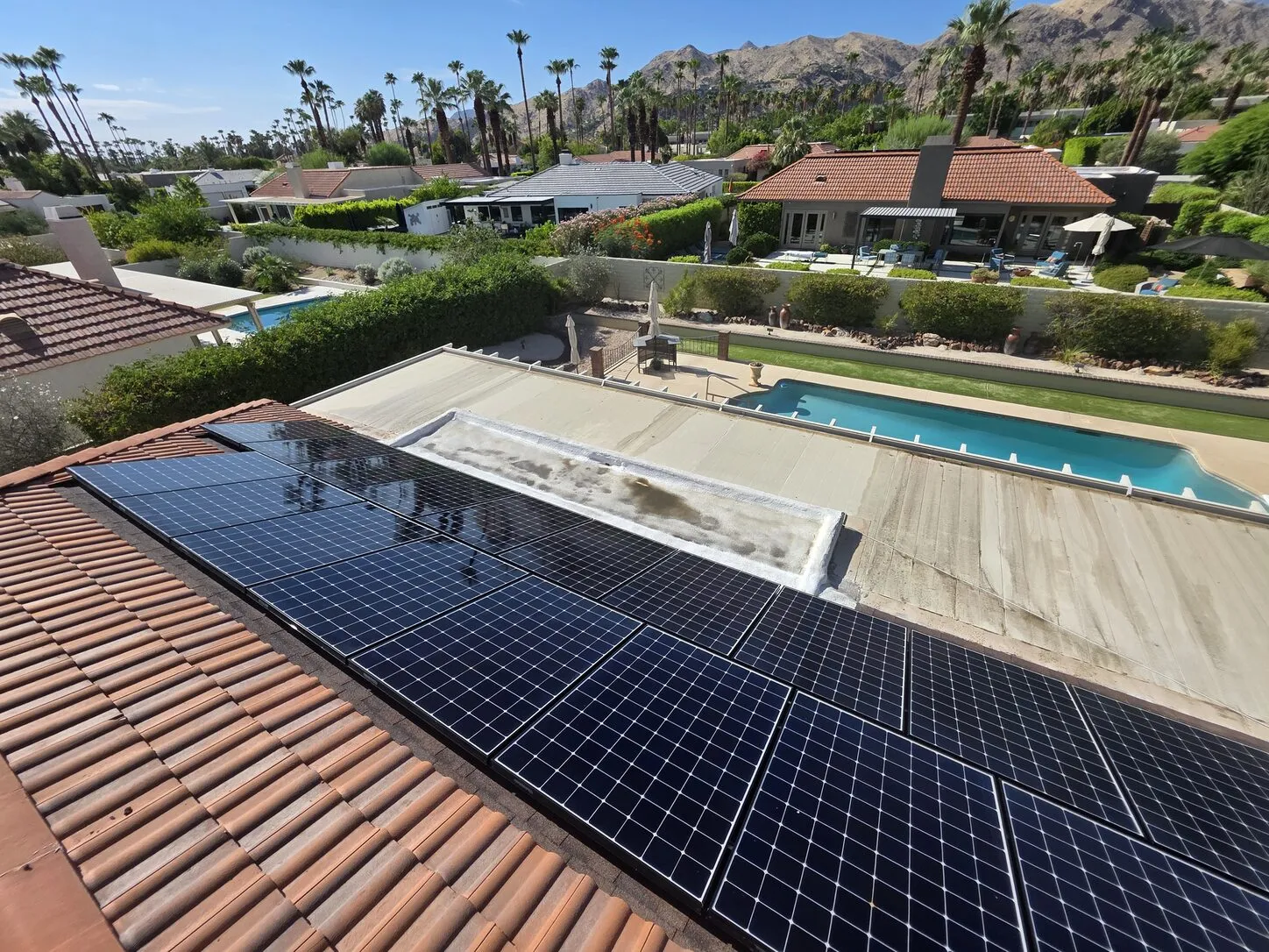 Job photo: freshly cleaned solar panels on a Palm Springs tile roof, with a pool and mountains behind