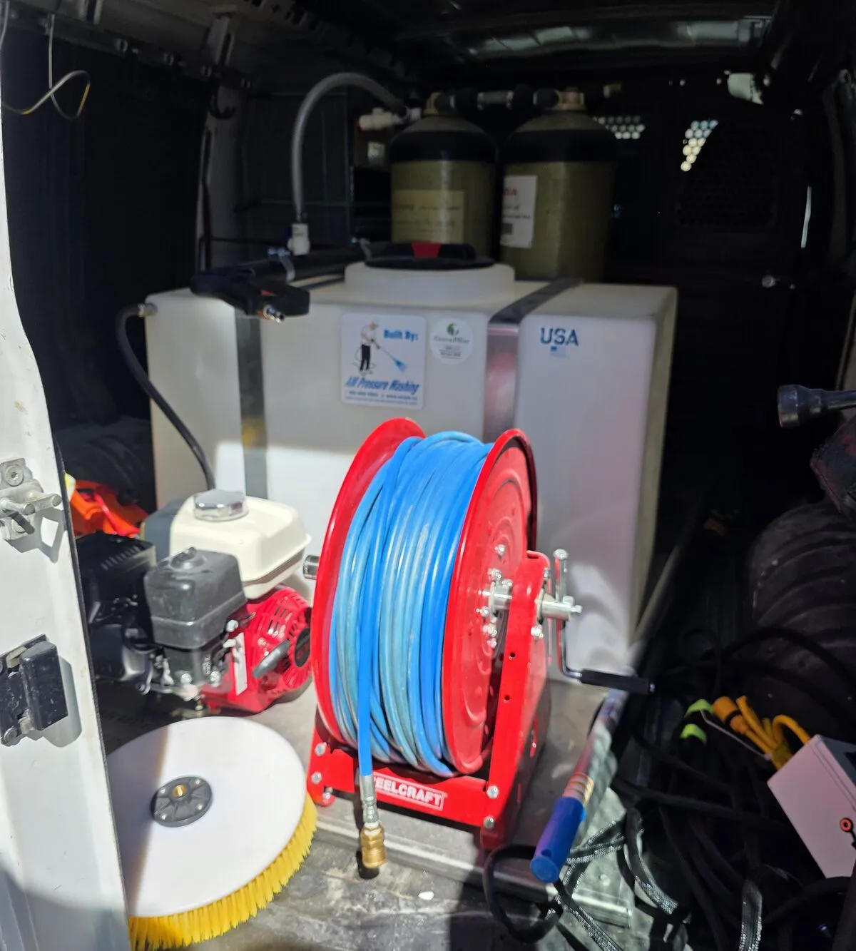Photo: the water system in the Clear Flow van, with two filter tanks over a water tank, a hose reel and a round soft brush